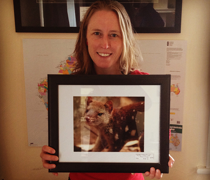 Jane Hutchinson with the framed photograph of a spotted quoll from Laura Ashby's collection.